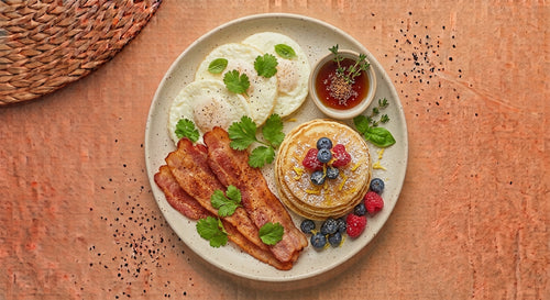 All American — egg whites with crisp turkey bacon and a stack of mini buttermilk pancakes with fresh berries and a side cup of syrup