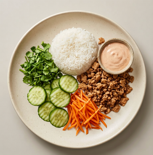 Banh Mi Babe — sweet ground turkey, jasmine rice, cucumber, shredded carrots, and cilantro on a cream plate