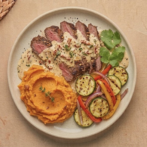 Baton Rouge — sliced grass-fed skirt steak in garlicky Cajun cream sauce with mashed sweet potatoes and sautéed zucchini, pepper and onion mix