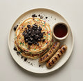 The Birthday Stack — funfetti protein pancakes topped with Oreo crumbles, grilled chicken sausage links, and a syrup cup
