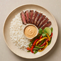 Calle Ocho — sliced carne asada over jasmine rice with sautéed fajita peppers and chipotle sauce on a cream plate